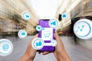 Pessoa segurando celular com ícones digitais de compras e atendimento online ao redor