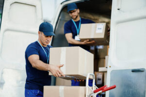 Trabalhadores de logística carregando caixas de encomendas em van de entregas