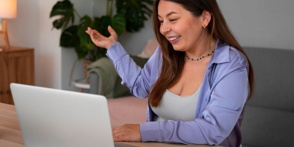 Mulher sorridente interagindo em chamada de vídeo pelo laptop em ambiente doméstico