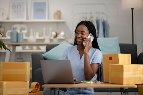 Mulher empreendedora atendendo cliente por telefone enquanto organiza vendas online